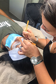stagiaire entrain de réaliser une extension de cils sur modèle pendant une formation