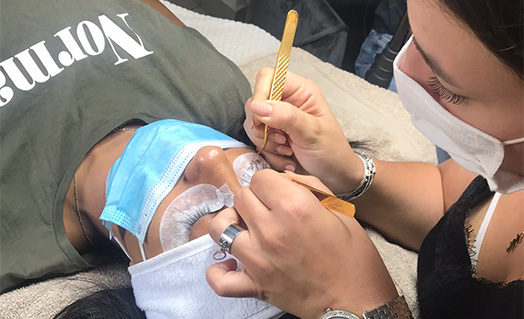 stagiaire entrain de poser des extensions de cils sur modèle formation