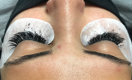 stagiaire entrain de poser des extensions de cils sur modèle formation